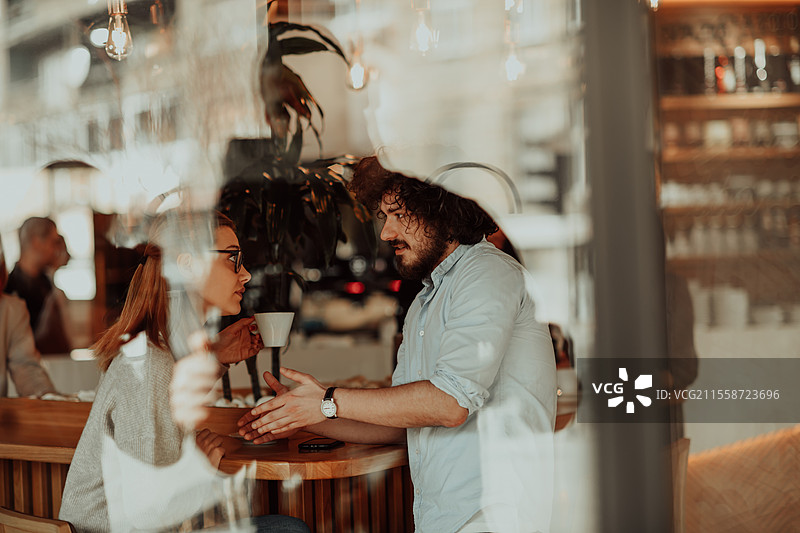 一位戴眼镜的女性和几位有非洲卷发的男性坐在咖啡馆里讨论商业项目。商业情侣在工作日后坐在咖啡馆里。图片素材