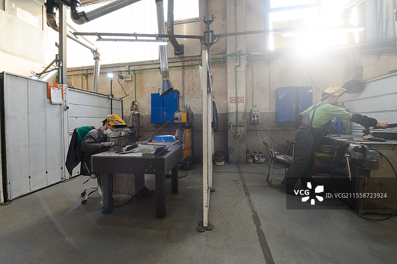 金属行业工人在工厂工作，佩戴防护口罩以应对冠状病毒或COVID-19疫情。高质量照片。金属行业工人在工厂工作，佩戴防护口罩以应对冠状病毒或COVID-19疫情。图片素材