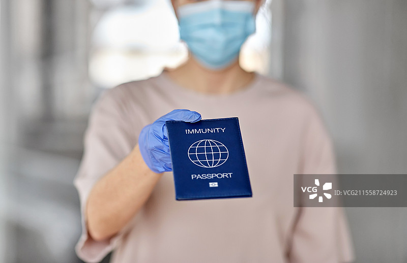 健康保护、疫苗接种和疫情概念 - 戴着口罩和手套的女性手持免疫护照的特写。图片素材