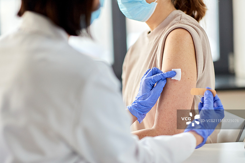 健康、医学和疫苗接种概念 - 医生在医院为患者贴上粘性医疗创可贴的特写镜头。医生为患者贴上创可贴的特写镜头。图片素材