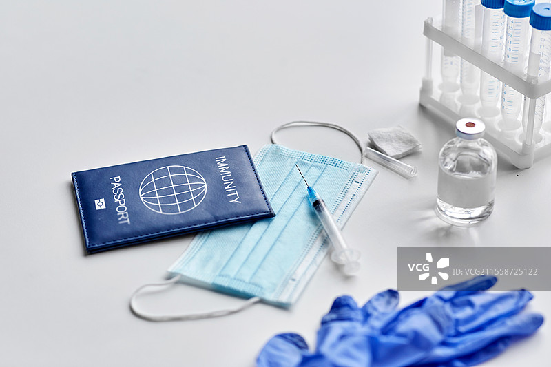 医学、疫苗接种和医疗保健概念 - 免疫护照与口罩、注射器、疫苗和带保护手套的试管放在白色桌子上。免疫护照、口罩、注射器、疫苗放在桌子上。图片素材