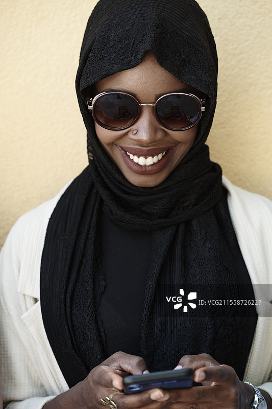 身穿传统伊斯兰服装的非洲女商人正在使用智能手机图片素材