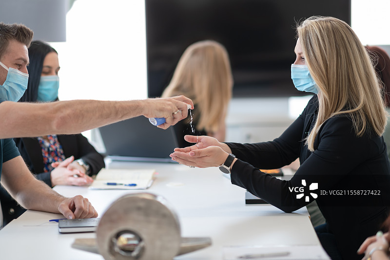 商务人士在会议上使用抗菌洗手液以防止冠状病毒疫情的新常态，COVID-19疫情概念图片素材