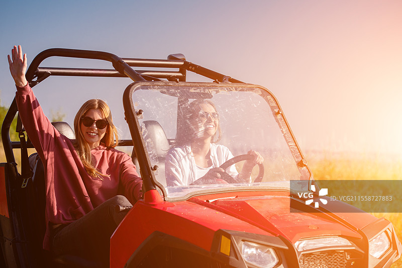 两个年轻快乐兴奋的女性在阳光明媚的日子里驾驶越野车，享受山间大自然。图片素材