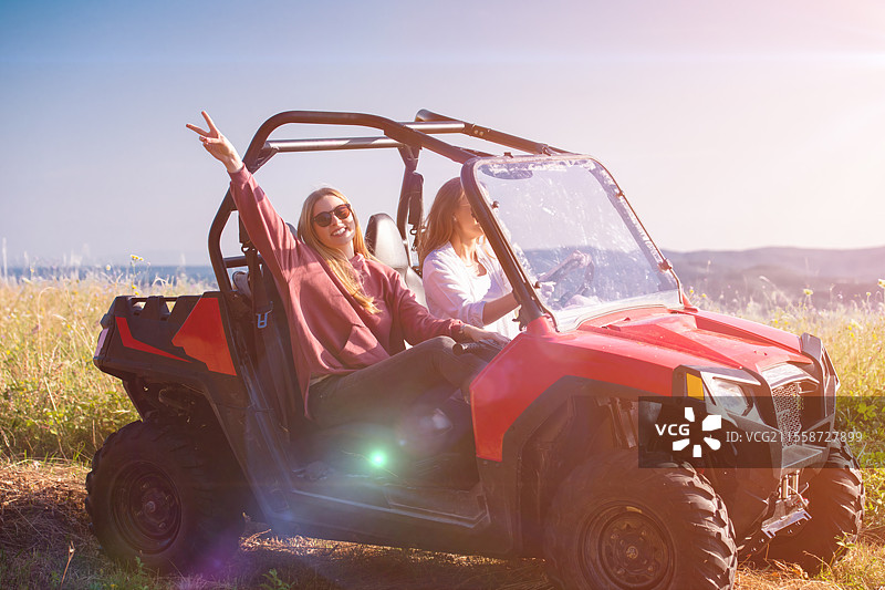 两个年轻快乐兴奋的女性在阳光明媚的日子里驾驶越野车，享受山间大自然。图片素材