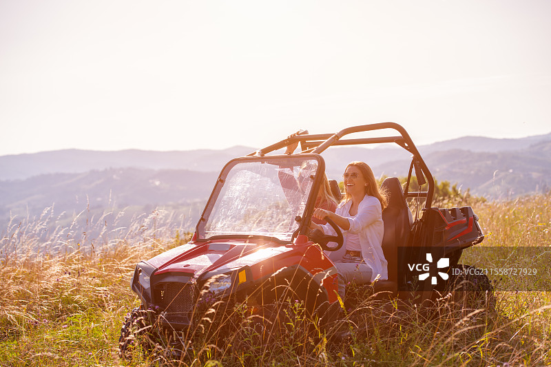 两个年轻快乐兴奋的女性在阳光明媚的日子里驾驶越野车，享受山间大自然。图片素材