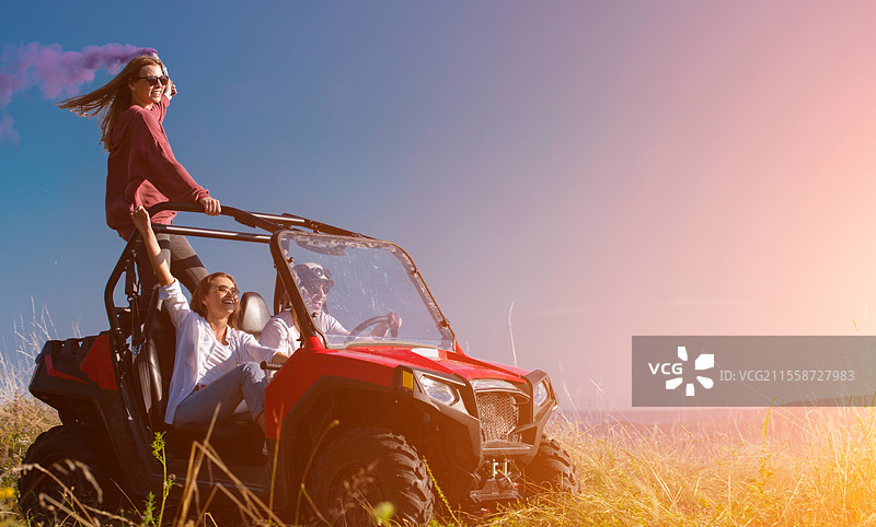 一群年轻快乐兴奋的人在美丽的阳光明媚的日子里，手持五彩缤纷的火把，驾驶越野车在山间大自然中尽情享受乐趣。图片素材