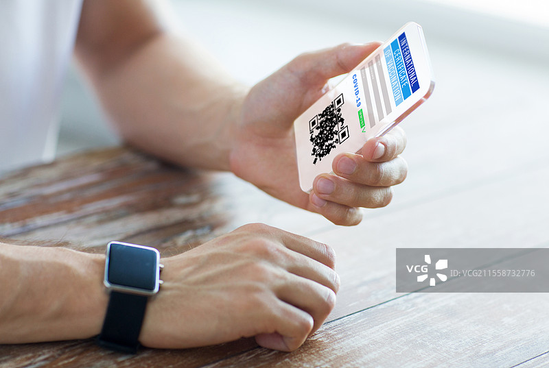 科技与医疗概念 - 男性手部特写，手握透明智能手机，屏幕上显示虚拟免疫护照或国际疫苗接种证明。手中持有虚拟免疫护照的智能手机。图片素材