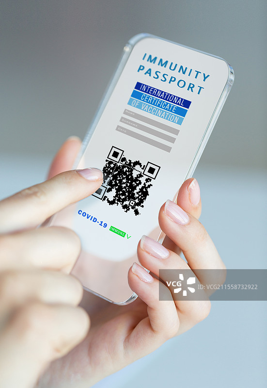 冠状病毒、科技与健康概念 - 特写镜头显示女性的手握着透明智能手机，屏幕上显示国际新冠疫苗接种证明。手中握着带有接种证明的手机。图片素材