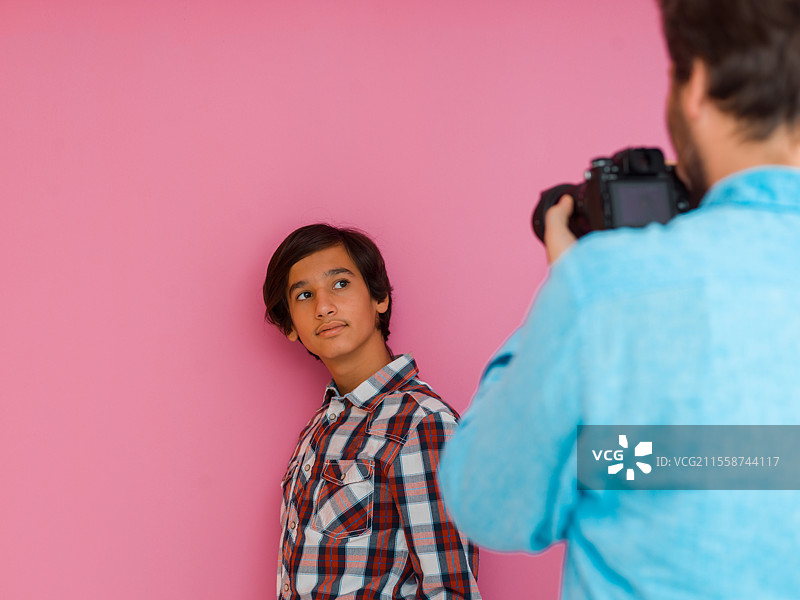 一张父亲和儿子在紫色墙壁前拍摄家庭照片的照片。选择性对焦。高质量照片。图片素材