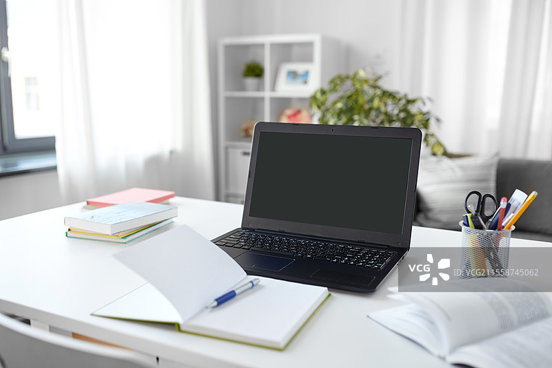 室内、教育和商业概念 - 家庭办公室桌上的打开笔记本电脑、笔记本和书籍。家庭办公室桌上的笔记本电脑、笔记本和书籍。图片素材