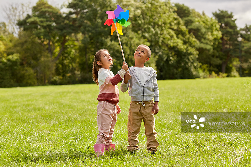 童年、休闲和人们的概念 - 快乐的孩子们在公园里玩风车，享受乐趣。图片素材