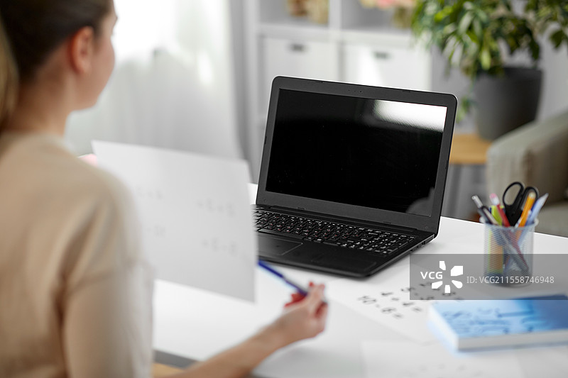 远程教育、学校和人们的概念 - 女性数学教师在家中使用笔记本电脑进行在线数学课程。数学教师在家中进行在线课程。图片素材