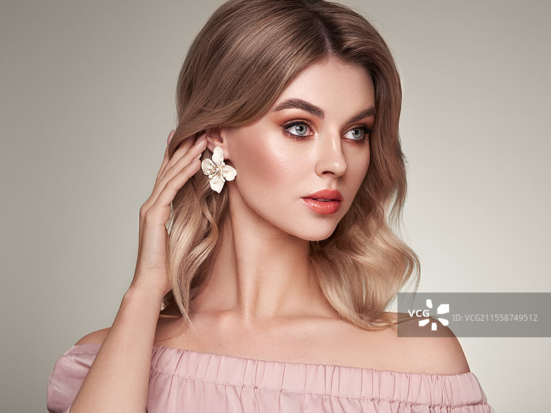 一位美丽的年轻女性，拥有闪亮的波浪形金发。健康肌肤的特写肖像。美容、护肤和水疗。图片素材