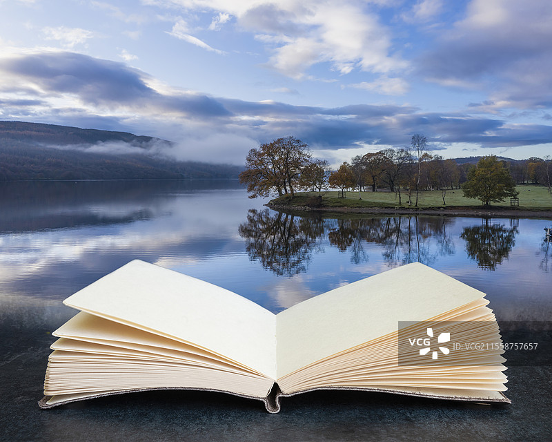令人惊叹的数字合成图像，展示了在想象中的翻开的阅读书页上，康尼斯顿湖的空中无人机风景。图片素材