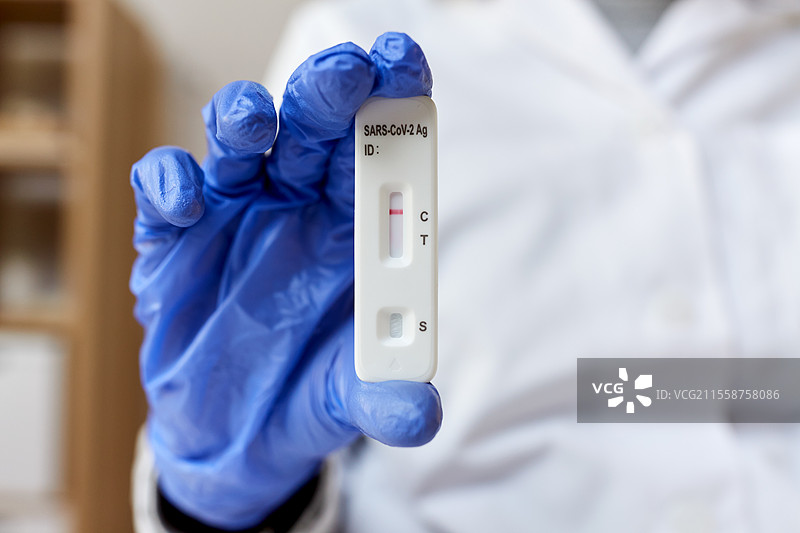 医学、隔离和疫情概念 - 医生戴着医疗手套的手握着阴性的自我检测新冠病毒测试。医生手中握着阴性新冠病毒测试的特写。图片素材