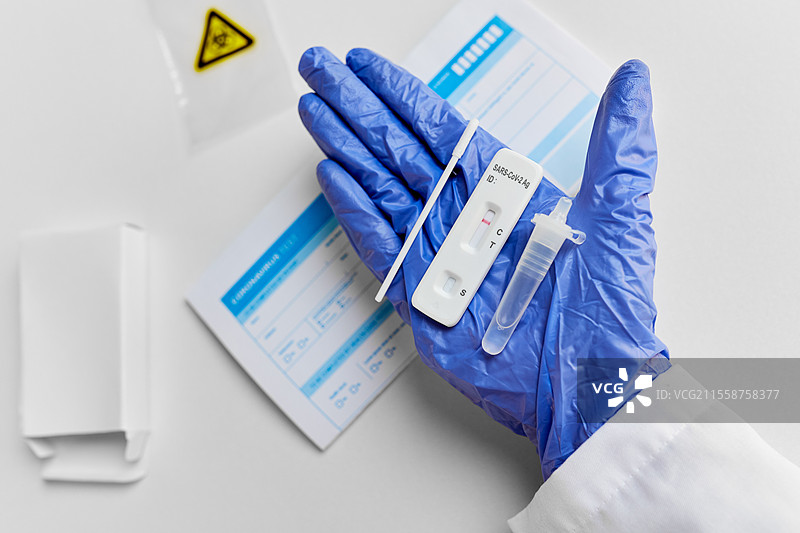 医学、隔离和疫情概念 - 医生戴着医疗手套的手在白色背景上握着阴性的自我检测冠状病毒测试。手部特写显示阴性冠状病毒测试。图片素材