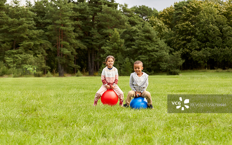 童年、休闲和人们的概念 - 快乐的孩子们在公园里跳跃着蹦蹦球。快乐的孩子们在公园里跳跃着蹦蹦球。图片素材