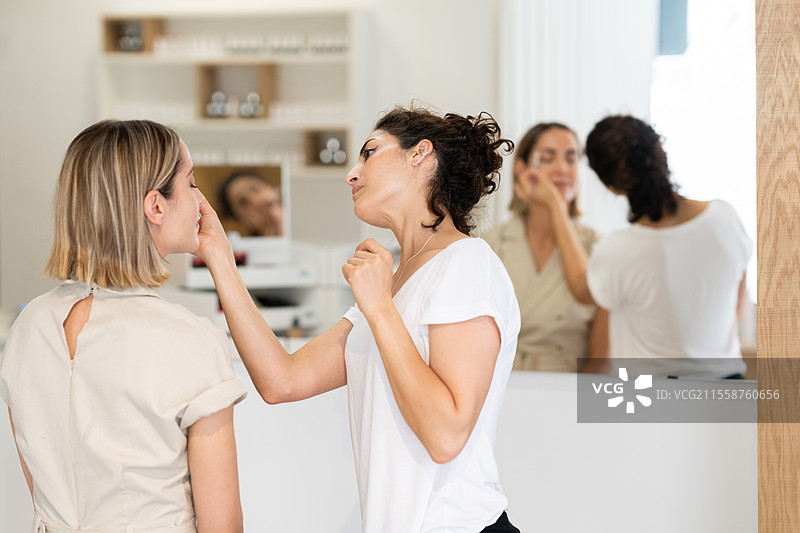 专业女性美容师在现代美容中心为女性进行护肤治疗。美容师正在为客户进行美容程序。图片素材