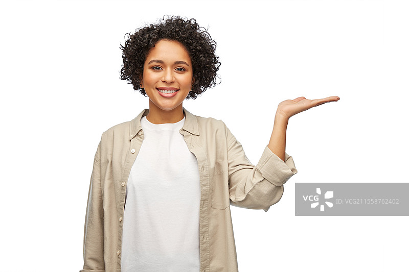 人们、种族和肖像概念 - 一位快乐微笑的女性穿着衬衫，手中握着一些想象中的东西，背景为白色。快乐微笑的女性手中握着一些东西。图片素材