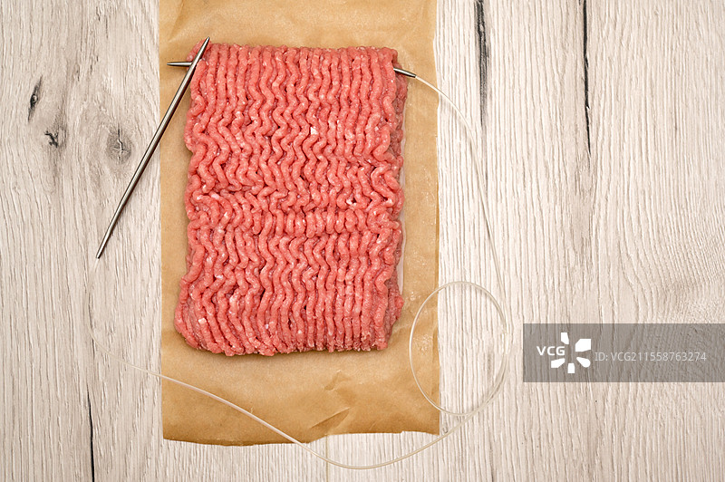 抽象的生牛肉剁碎自制肉馅与编织针图片素材