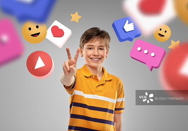 社交媒体与人们的概念 - 穿着马球衫的快乐微笑男孩在灰色背景下展示两个手指或和平手势。快乐的男孩在互联网图标前展示和平手势。图片素材