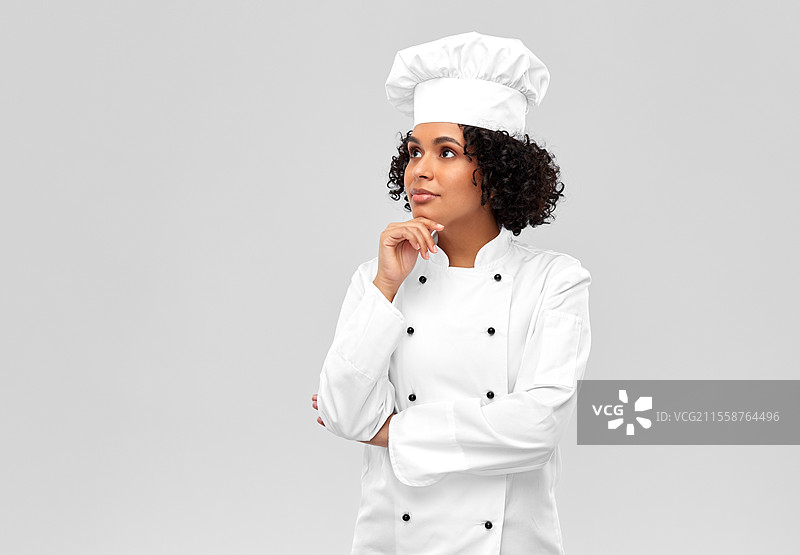 烹饪、烹饪艺术和人物概念 - 思考中的女性厨师，穿着白色厨师帽和外套，背景为灰色。思考中的女性厨师，背景为灰色。图片素材