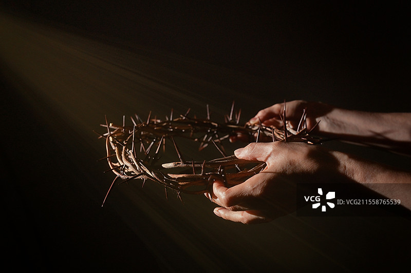 手中捧着的荆棘冠与阳光射线的特写图片素材