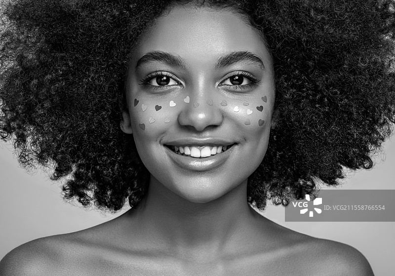 非洲裔美国女孩的美丽肖像，蓬松的非洲发型。美丽的黑人女性。一个女人的脸上装饰着心形图案。情人节照片。图片素材