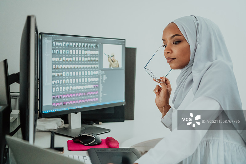 年轻的非裔美国现代穆斯林女商人，佩戴头巾，身处创意明亮的办公室，背景有大屏幕。高质量照片。图片素材