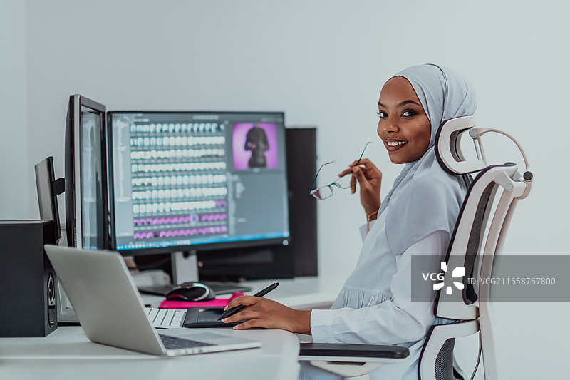 年轻的非裔美国现代穆斯林女商人，佩戴头巾，身处创意明亮的办公室，背景有大屏幕。高质量照片。图片素材