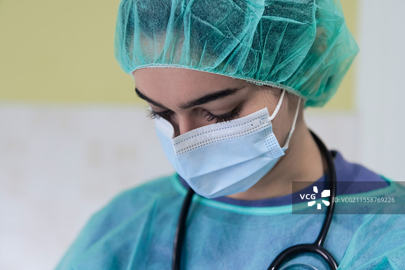 戴着防护口罩的悲伤和不堪重负的医生或护士肖像，因新冠病毒疫情而显得疲惫、沮丧和担忧。情绪紧张，医护工作者与COVID-19。图片素材