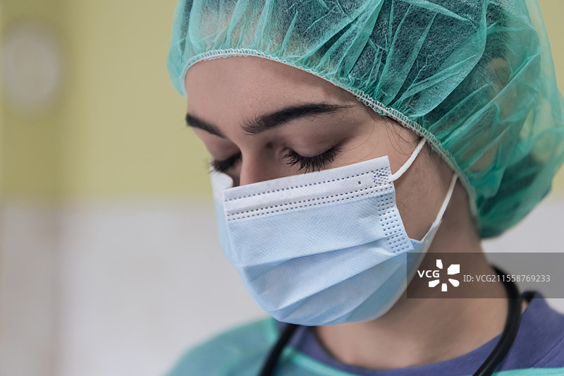 戴着防护口罩的悲伤和不堪重负的医生或护士的肖像，因新冠病毒疫情而显得疲惫、沮丧和担忧。情绪紧张，医护工作者与COVID-19。图片素材