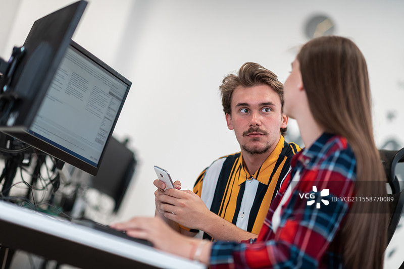 现代开放式初创公司办公室中，一对商务情侣正在使用平板电脑和台式电脑共同合作项目。选择性对焦。高质量照片。图片素材