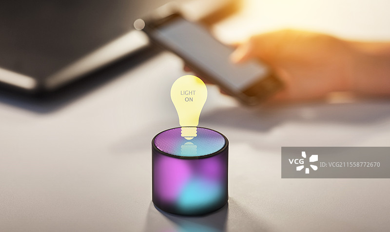 科技与人工智能概念 - 发光的智能音箱与桌上的虚拟灯泡图标，以及灯泡的虚拟全息图。智能音箱与虚拟灯泡的全息图。图片素材