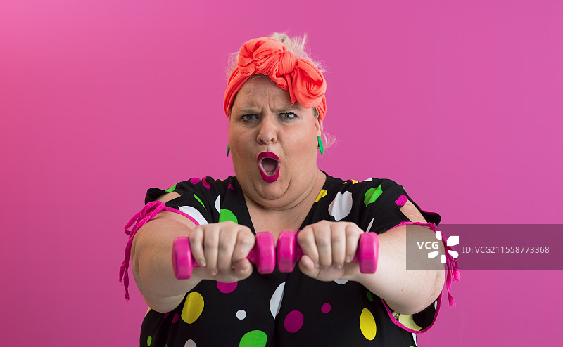 胖女人在家节食，健身和健康饮食。大个子女性与运动。健康、健身和运动的概念。加大码年轻女性在粉色背景下用哑铃锻炼。高质量照片。胖女人在家节食，健身和健康饮食。大个子女性与运动。健康、健身和运动的概念。加大码年轻白人女性在舒适的卧室内用哑铃锻炼。图片素材