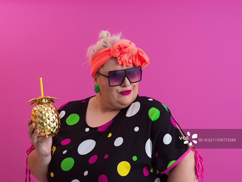 超重的丰满女性，胖女人，胖女孩，微胖，手持金色菠萝，背景为粉色 - 生活方式 女性饮食减肥超重问题概念。高质量照片。图片素材