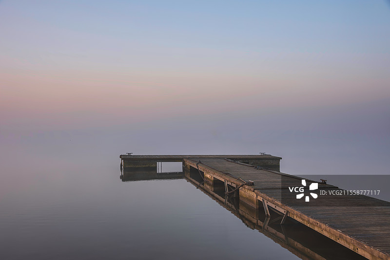 春天日出时分，水库湖泊的壮丽景色，晨光洒在水面上，薄雾增添了氛围。图片素材
