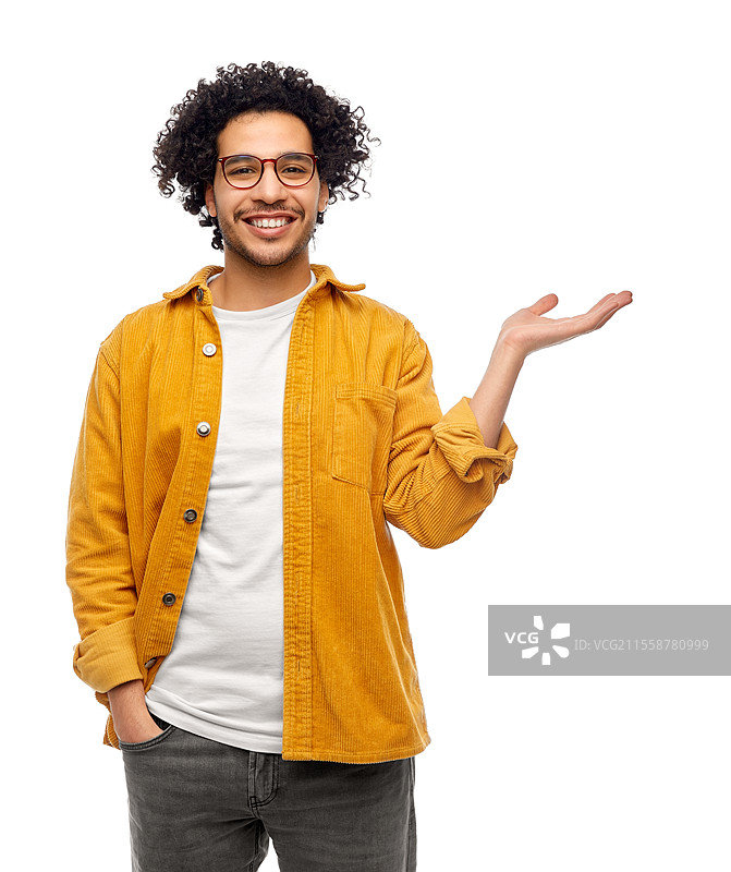 时尚与人群概念 - 一位戴眼镜、穿着黄色夹克的快乐微笑男子在白色背景前手中拿着某物。戴眼镜的快乐男子手中拿着某物。图片素材