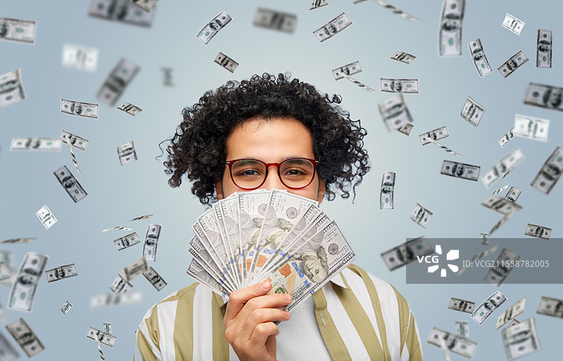 金融、货币和人们的概念 - 开心的男人在灰色背景下手持数百美元的钞票。开心的男人与美元。图片素材