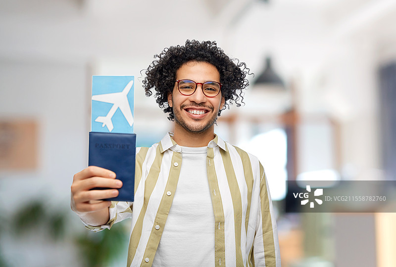 旅行、旅游和人们的概念 - 微笑的男子手持护照和机票，背景为办公室。图片素材