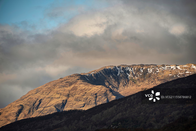 美丽的冬季风景，沿着洛赫利文湖，经过巴拉赫利什桥，远处是白雪覆盖的山脉和戏剧性的天空。图片素材