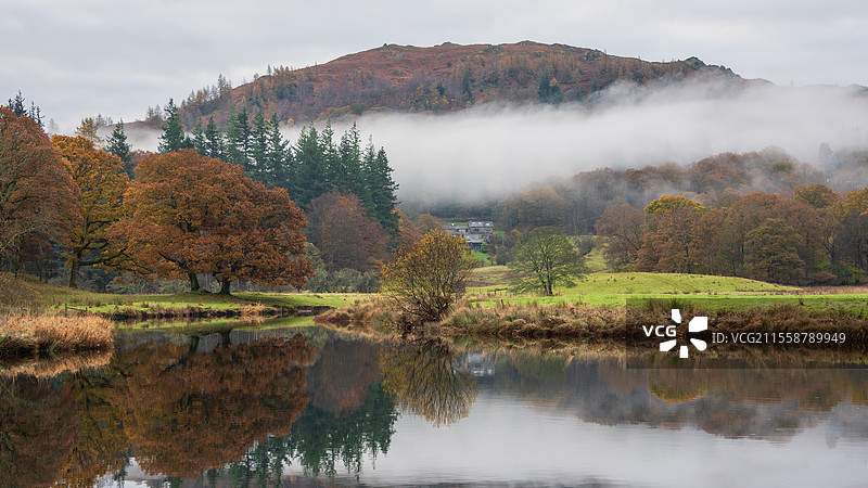 湖区布拉瑟河的壮丽秋季风景，远望朗代尔山脊，河面上笼罩着雾气，周围是生机勃勃的森林。图片素材