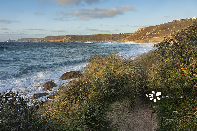 康沃尔州的塞农湾美丽的日落景观，从草地沙丘俯瞰，天空阴郁，海面长时间曝光的运动效果。图片素材