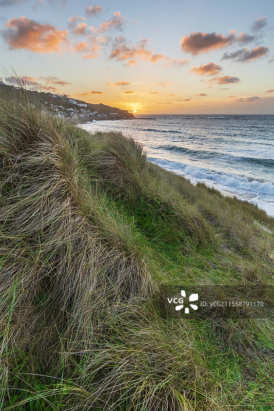 康沃尔州塞农湾的美丽风景，日落时分从草地沙丘上俯瞰，天空阴郁，海面长时间曝光的运动效果。图片素材