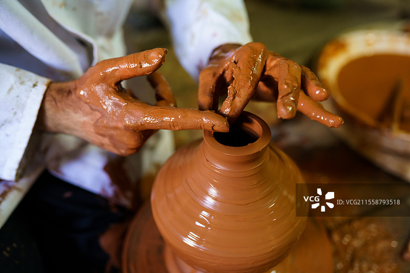 工匠在阿拉伯陶轮上塑造陶器，地点位于法哈劳萨，这是格拉纳达著名传统陶器的工厂。工艺概念。工匠在阿拉伯陶轮上塑造陶器。图片素材