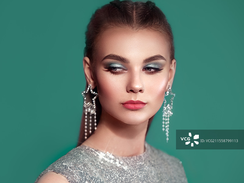 佩戴珠宝的美丽女性肖像。美容时尚。睫毛。化妆眼影。护发和美容产品。穿着银色连衣裙的模特。图片素材
