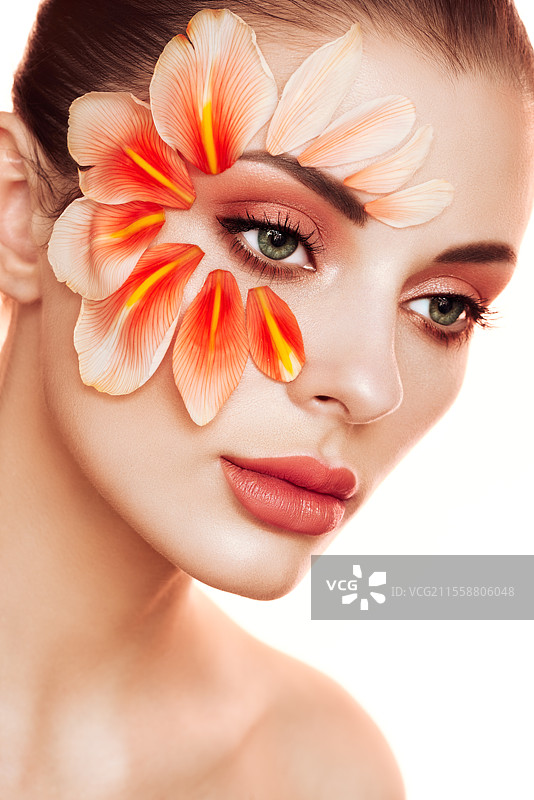 美丽年轻女性的肖像，妆容中有花瓣。棕发女性奢华妆容。完美肌肤。睫毛。化妆眼影。图片素材