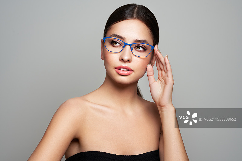 戴眼镜的长睫毛女性。视力矫正。视力不佳。眼镜框。化妆，美容。特写，微距。图片素材
