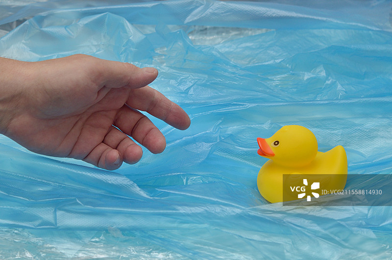 海洋塑料污染概念，黄色橡胶鸭玩具与人手图片素材
